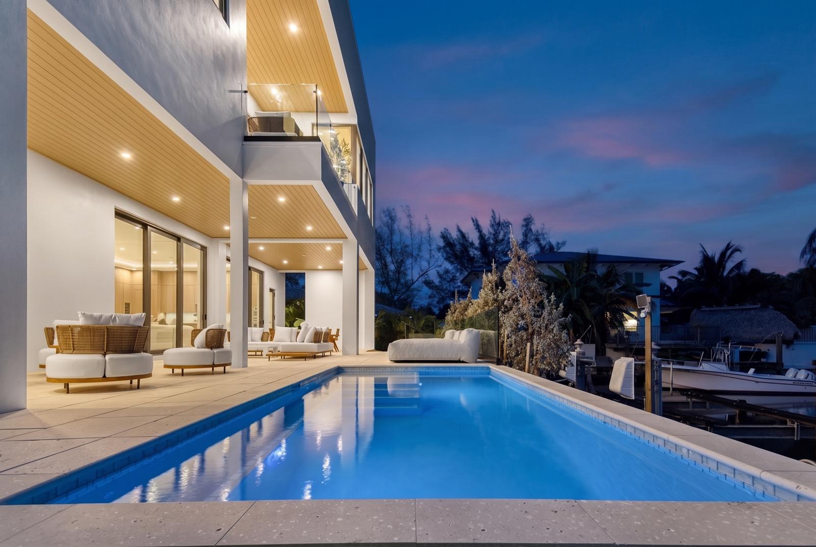 Twilight view of the pool, covered loggia and private dock at 252 SW 14th Place, Boca Islands